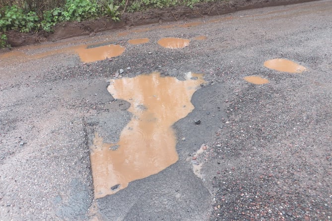 Potholes the width of the road at Moorlake, impossible to avoid and deep.  SR 3455
