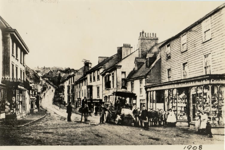 1908 An early bus parked in Modbury outside Trinick stationer, printer and cycle agent.