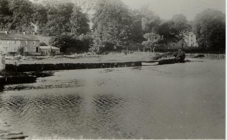 River Avon at Aveton Gifford.  Small boats in foreground.  Efford House in background through trees.