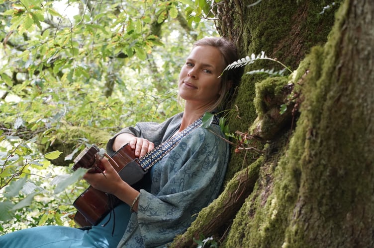 Charlotte Mabon with her guitar in a tree.