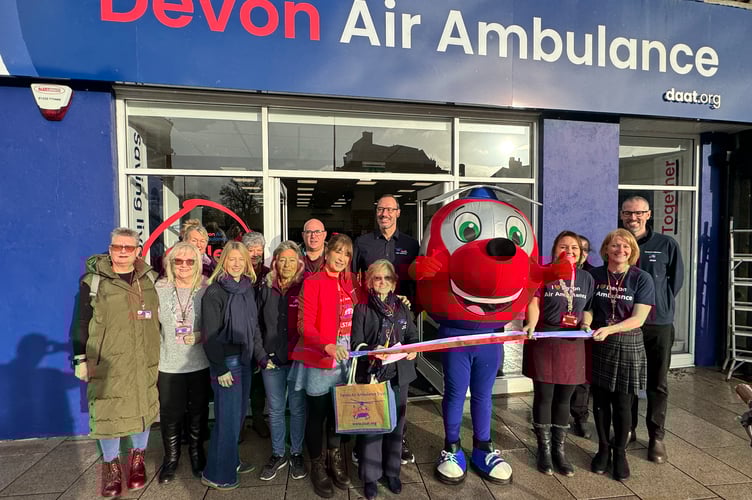 Devon Air Ambulance Founder and Life President Ann Ralli, centre, cut a ribbon to officially open its newest charity shop. AQ 0035