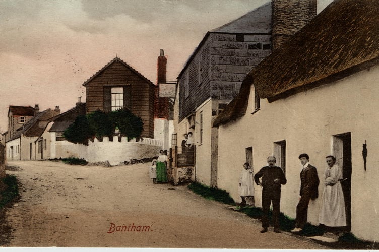 Pre-1908 view east up hill to junction at Bantham. Sloop Inn on right. People in street. Seaweed hung on wall of cottage by doorway.