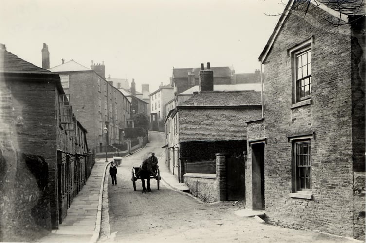Duncombe Street, Kingsbridge, looking west to Fore Street.   Man with wheelbarrow in background. Horses and cart coming down the hill